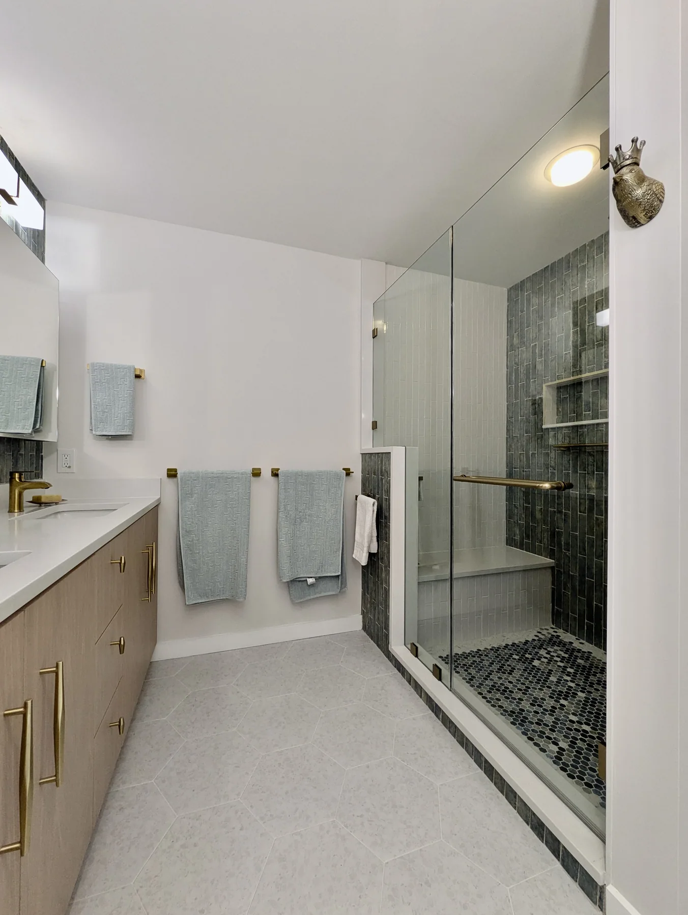 Bright bathroom featuring a double vanity, blue tile and glass shower enclosure