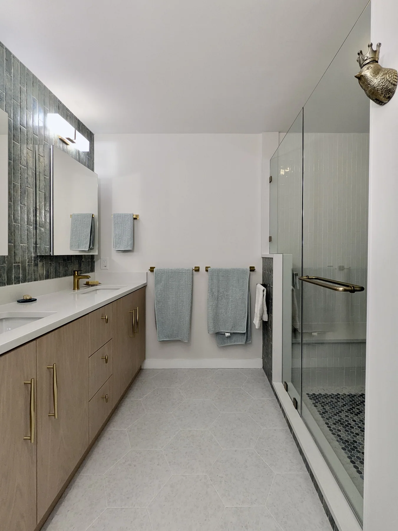 Remodeled bathroom with a light wood double vanity and glass shower
