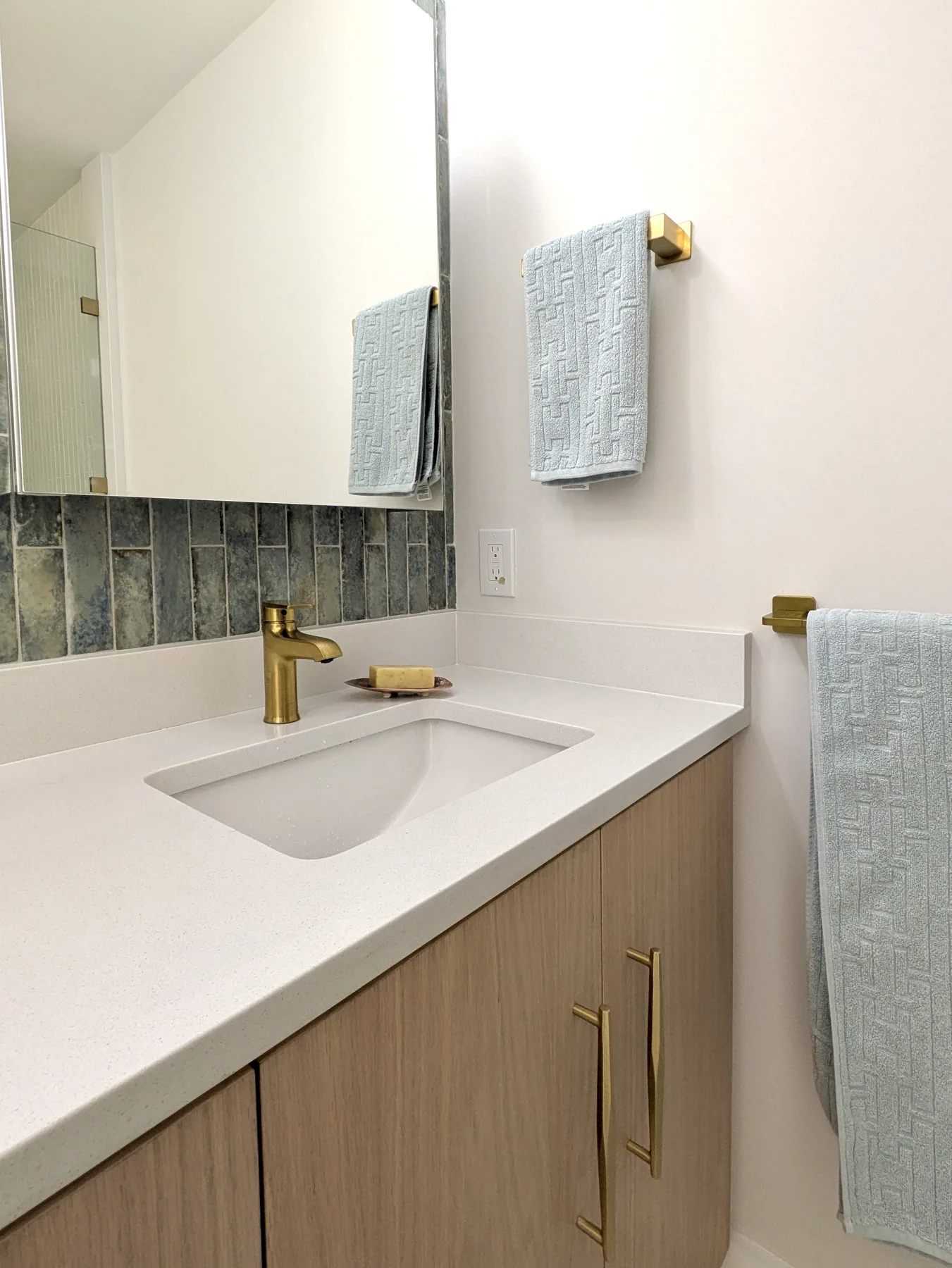 Vanity sink detail White integrated bathroom sink with brass faucet and light wood cabinet