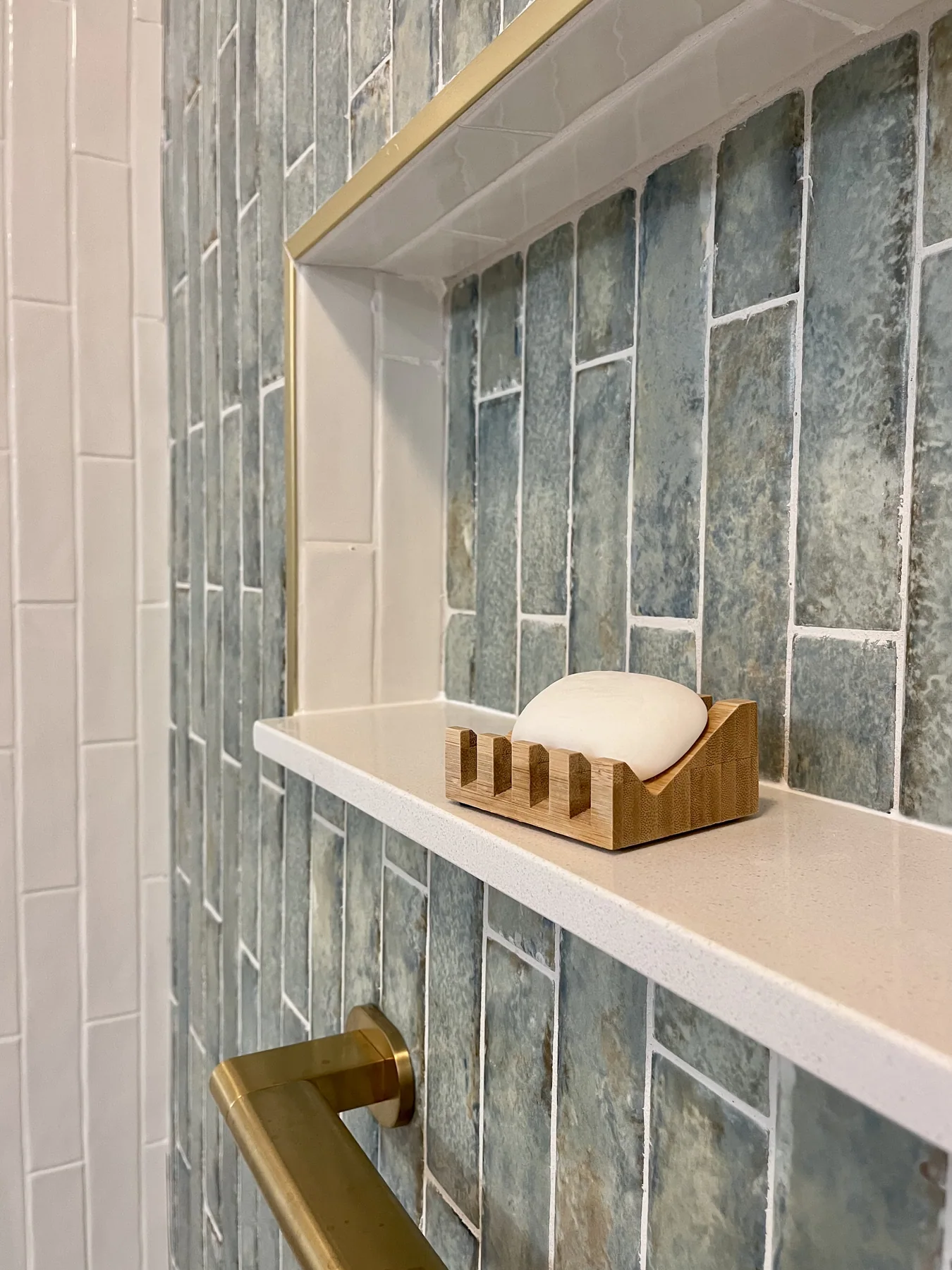 Recessed shower niche set into blue textured tile beside brass shower hardware