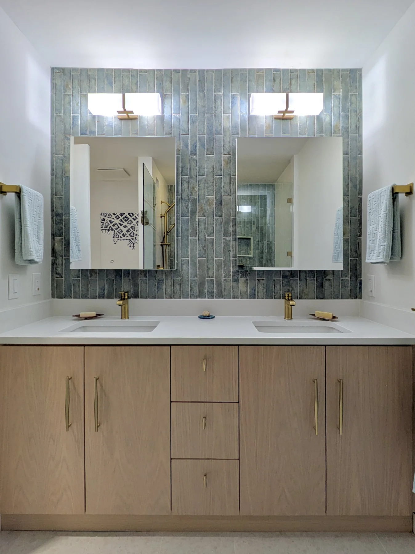 Coastal bathroom double vanity Double vanity with light wood cabinetry, white countertop and blue tile backsplash