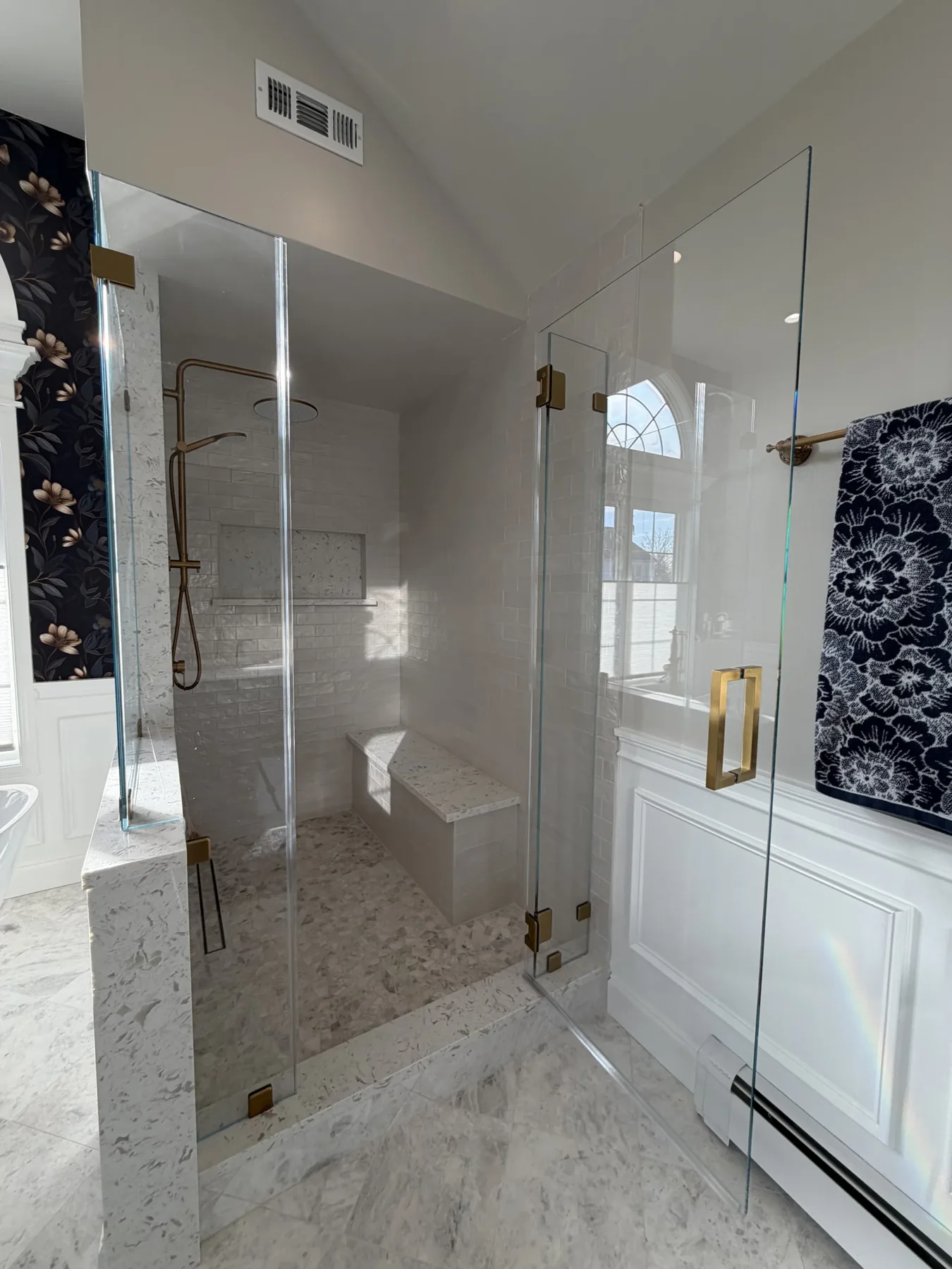 Frameless Glass Shower with Bench and Brass Hardware Frameless glass shower with brass hardware, white subway tile, a built-in bench and recessed niche